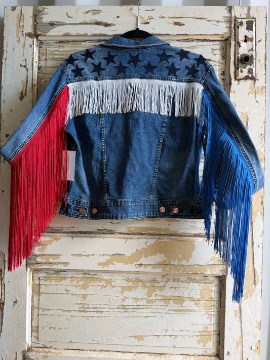 Denim jacket with colorful fringe on a rustic wooden door